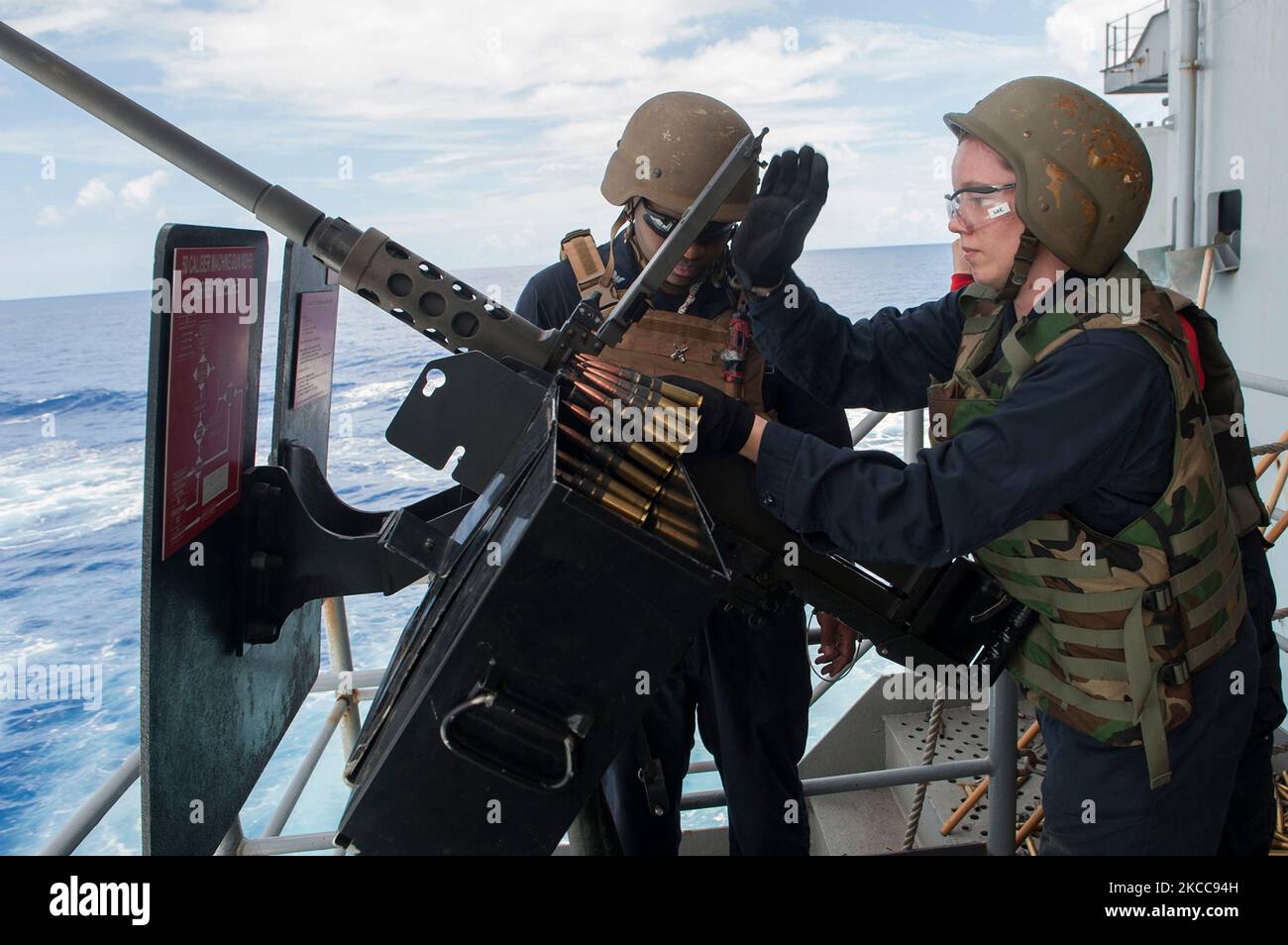 Aviation Ordnanceman che carica una mitragliatrice calibro M2HB .50. Foto Stock