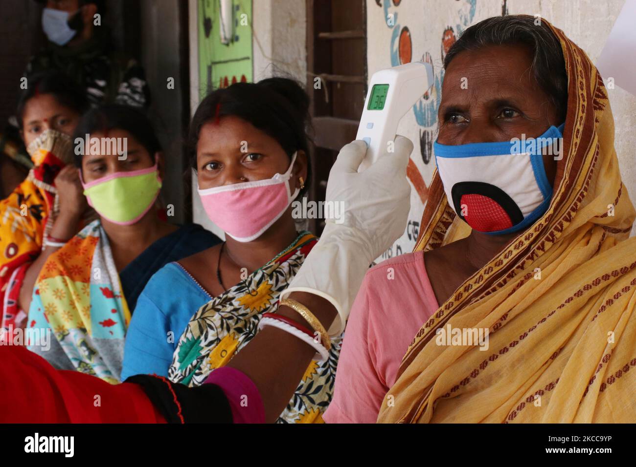 Gli operatori sanitari controllano la temperatura corporea degli elettori prima di entrare in un seggio elettorale per esprimere il loro voto durante le elezioni legislative dello Stato, a Haripal, distretto di Hooghly, a circa 50 km da Kolkata, India il 6 aprile 2021. (Foto di Debajyoti Chakraborty/NurPhoto) Foto Stock