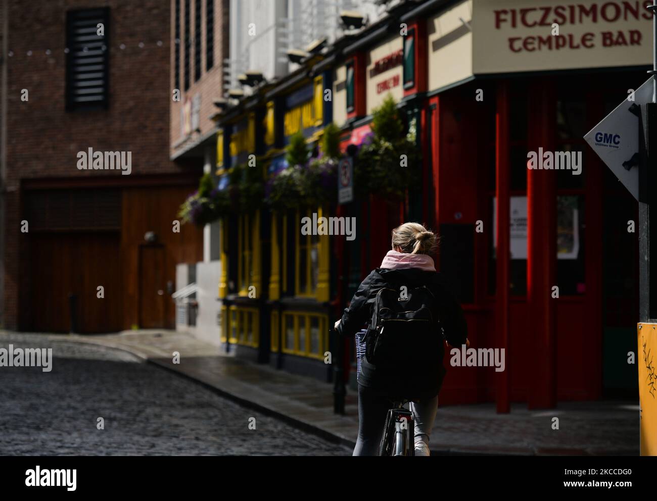 Una donna si mette in bicicletta in una strada vuota accanto a un pub chiuso nel Temple Bar di Dublino durante il blocco di livello 5 COVID-19. Giovedì, 8 aprile 2021, a Dublino, Irlanda. (Foto di Artur Widak/NurPhoto) Foto Stock