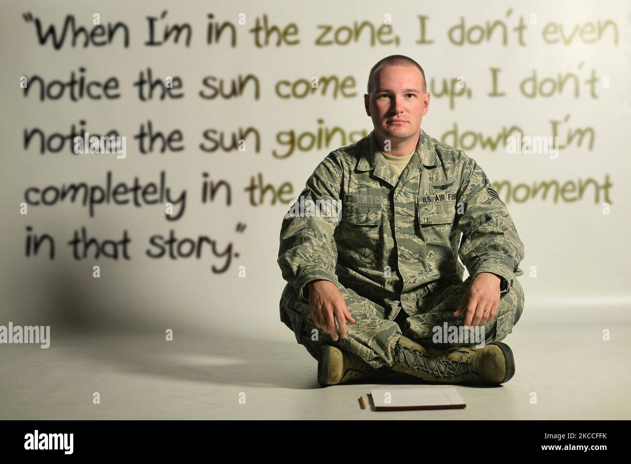 Un Airman dell'aeronautica degli Stati Uniti seduto sul pavimento con la scrittura di una storia corta immaginaria sullo sfondo. Foto Stock