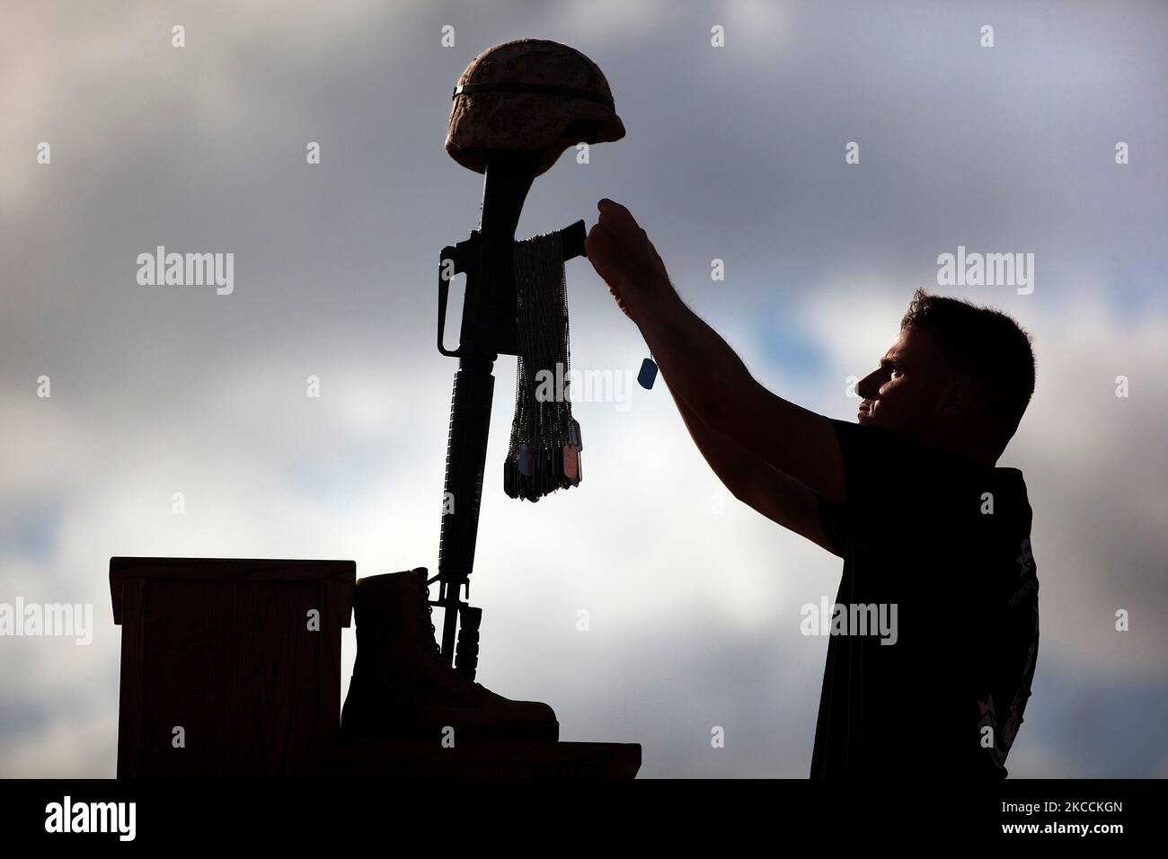 Una marina statunitense posiziona il tag di un cane caduto su una croce del campo di battaglia. Foto Stock