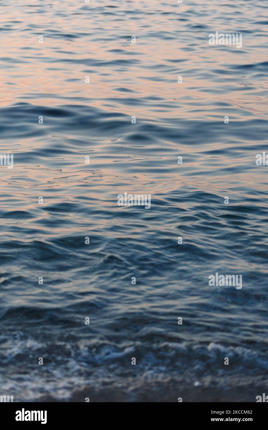 Ripple acqua mare oceano superficie con luce tramonto dorato. Primo piano dell'onda di mare Foto Stock