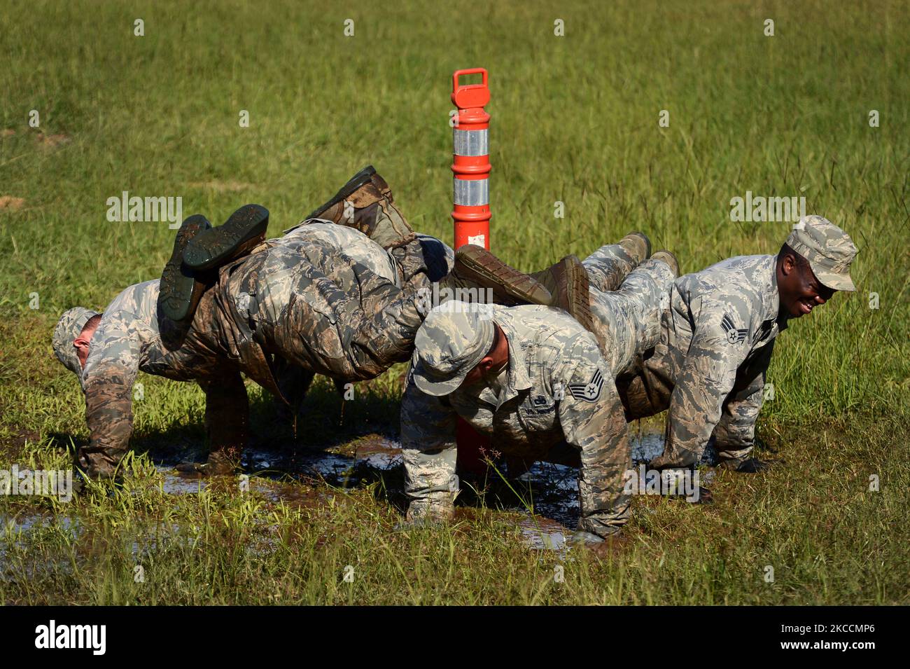 Gli airman eseguono un push-up di quattro uomini in una pozza di fango. Foto Stock