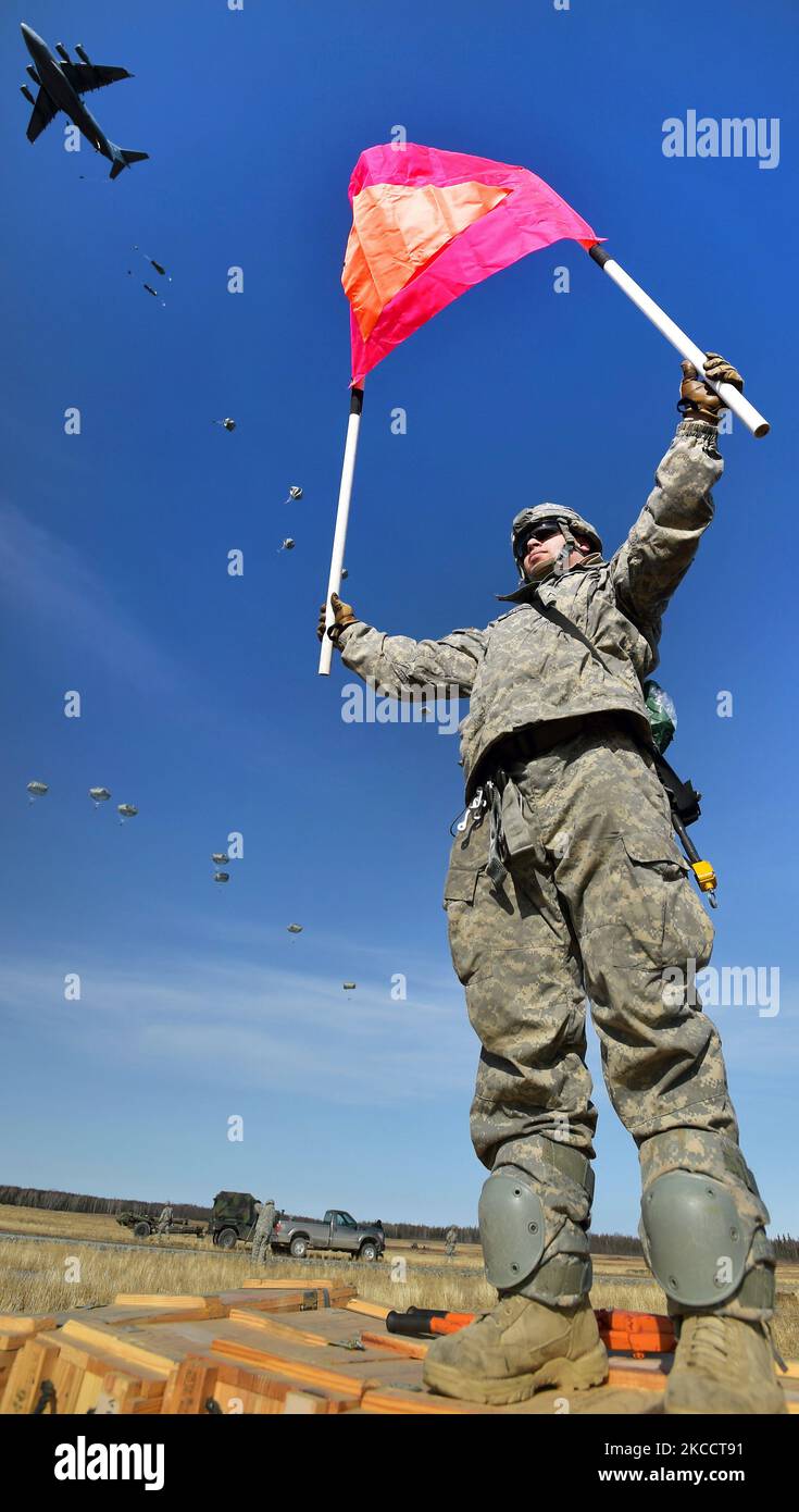 US Army Soldier tiene un gruppo di raduno mentre i paracadutisti conducono un assalto al paracadute. Foto Stock