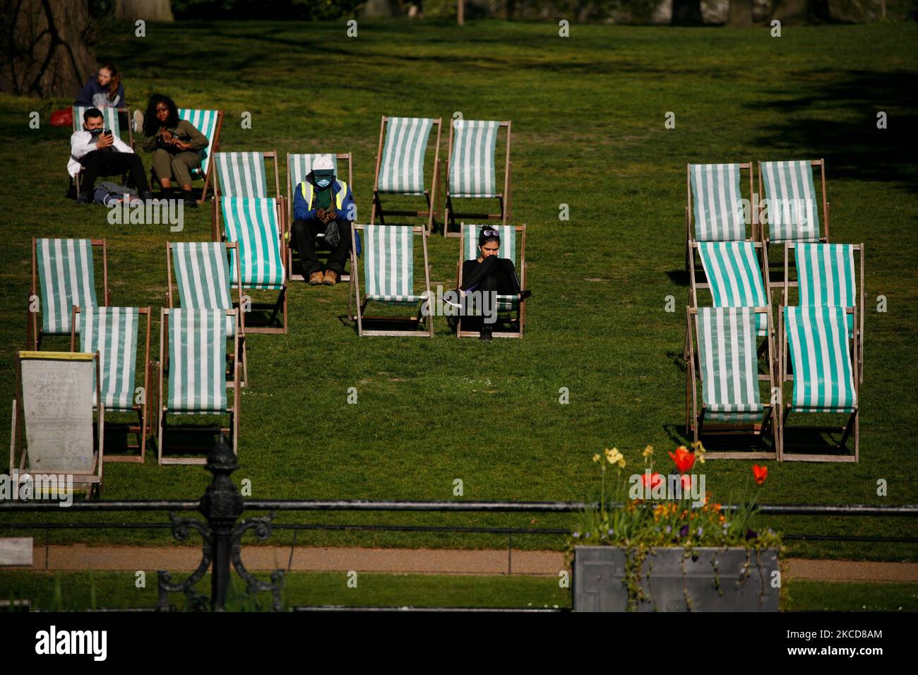 La gente si siede sulle sedie a sdraio in primavera a Kensington Gardens a Londra, Inghilterra, il 22 aprile 2021. (Foto di David Cliff/NurPhoto) Foto Stock