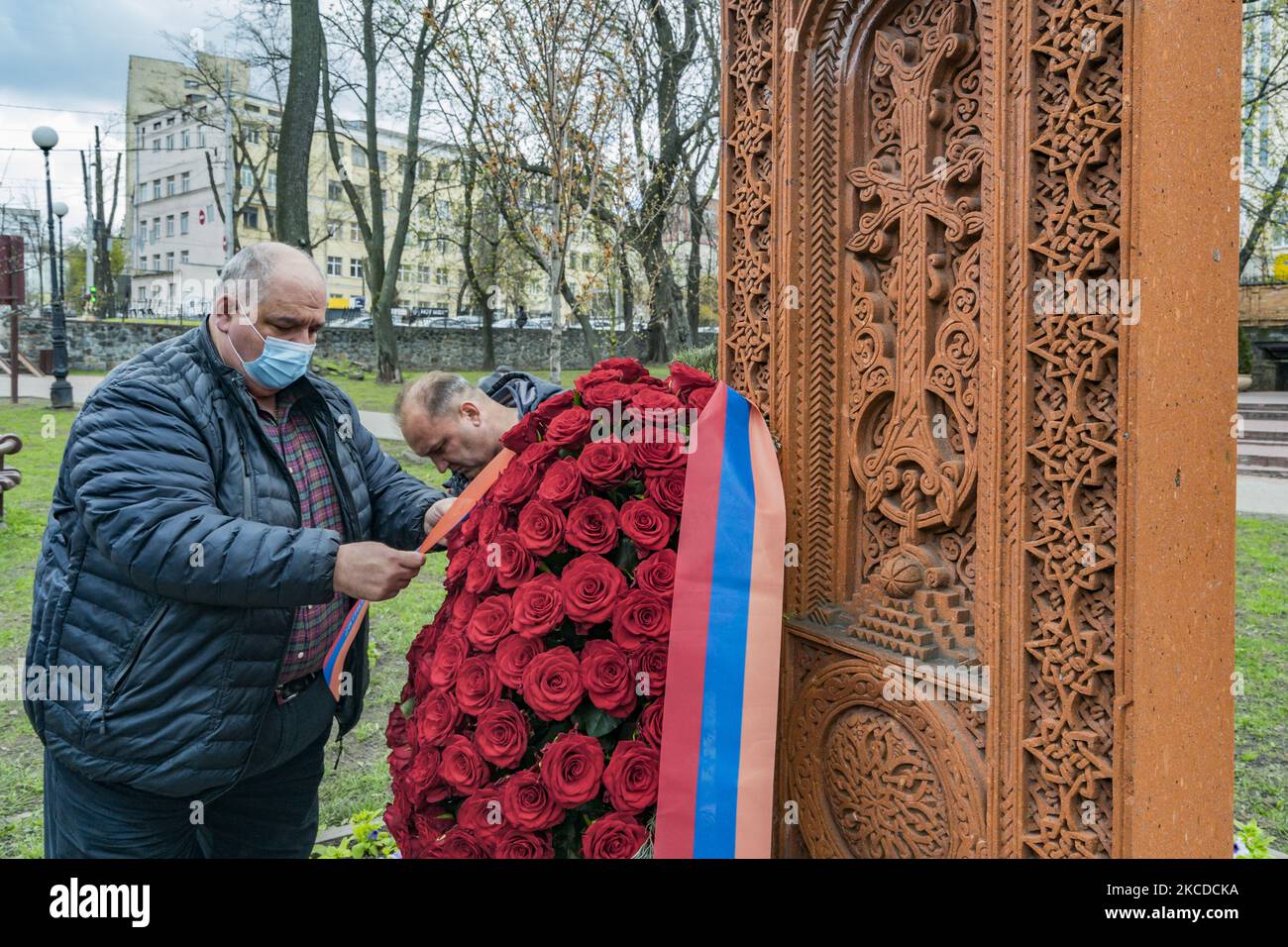 Un uomo prepara un'offerta di fiori vicino a un khachkar, una stele di pietra commemorativa della cultura armena, durante la Giornata della memoria del genocidio armeno a Kiev, Ucraina. (Foto di Celestino Arce/NurPhoto) Foto Stock