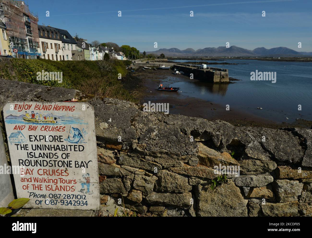 Una vista generale del porto di Roundstone durante la bassa marea, durante il blocco COVID-19. Da oggi, l'Irlanda sta allentando alcune restrizioni, tra cui la riapertura di impianti sportivi all'aperto, campi sportivi, campi da golf e da tennis. Le attività sportive senza contatto come il golf e il tennis possono riprendere. Riapriranno anche alcune attrazioni turistiche, tra cui giardini zoologici, fattorie animali aperte e siti storici, ma non parchi divertimenti. Tutti i servizi di ospitalità in queste aree saranno disponibili solo per i servizi da take-away e verranno applicati limiti di capacità. Il governo sta lavorando ai piani per riaprire gli hotel da presto Foto Stock