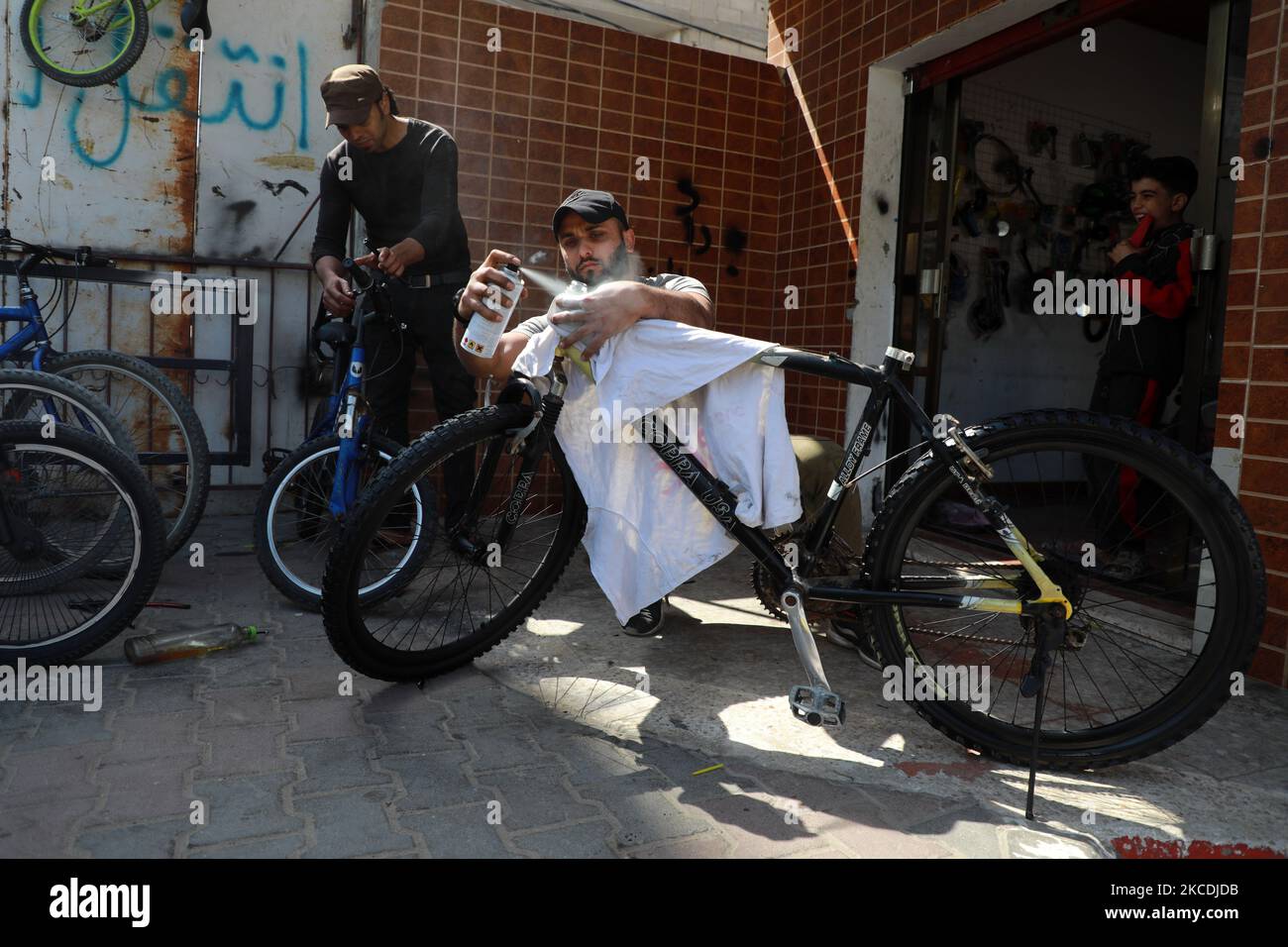 Un palestinese ripara un pneumatico da bicicletta nel suo laboratorio nella città di Gaza il 28 aprile 2021. (Foto di Majdi Fathi/NurPhoto) Foto Stock