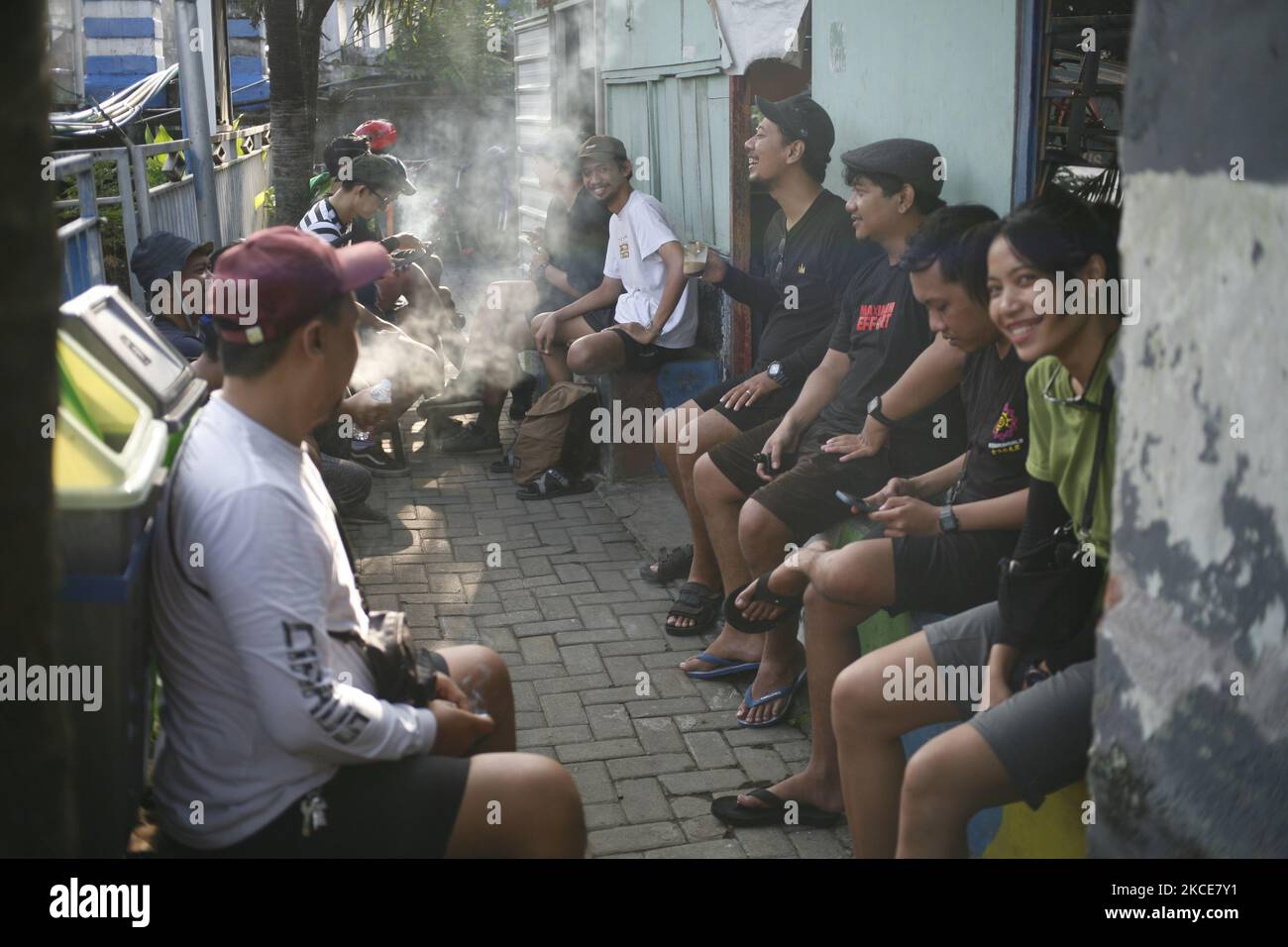 Gruppo asiatico di amici appeso fuori in caffè tradizionale o ristorante chiamato warung a Kediri, Eastjava, Indonesia. Foto Stock
