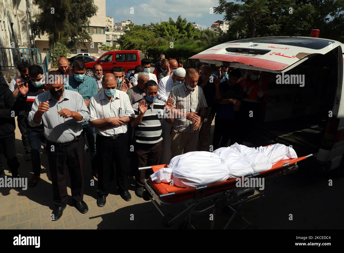 La gente offre preghiere funebri accanto al corpo di un palestinese, che è stato ucciso in un flare di violenza israelo-palestinese, a Gaza City 12 maggio 2021. (Foto di Majdi Fathi/NurPhoto) Foto Stock