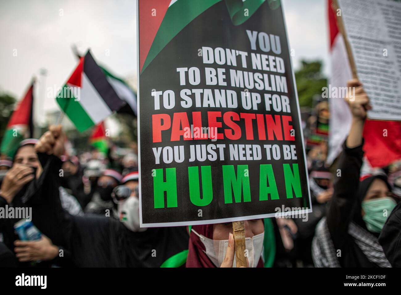 Un indonesiano ha un poster che recita: “Non è necessario essere musulmani per sostenere la Palestina è sufficiente essere umani” durante una protesta contro Israele a Giacarta il 21 maggio 2021. Centinaia di manifestanti hanno organizzato un raduno al di fuori dell'ambasciata degli Stati Uniti a Giacarta in solidarietà con il popolo palestinese a seguito di violenti scontri tra le forze di sicurezza israeliane e i palestinesi, esortando Israele a fermare gli attacchi a Gaza, in cui sono stati uccisi anche donne e bambini. (Foto di Afriadi Hikmal/NurPhoto) Foto Stock