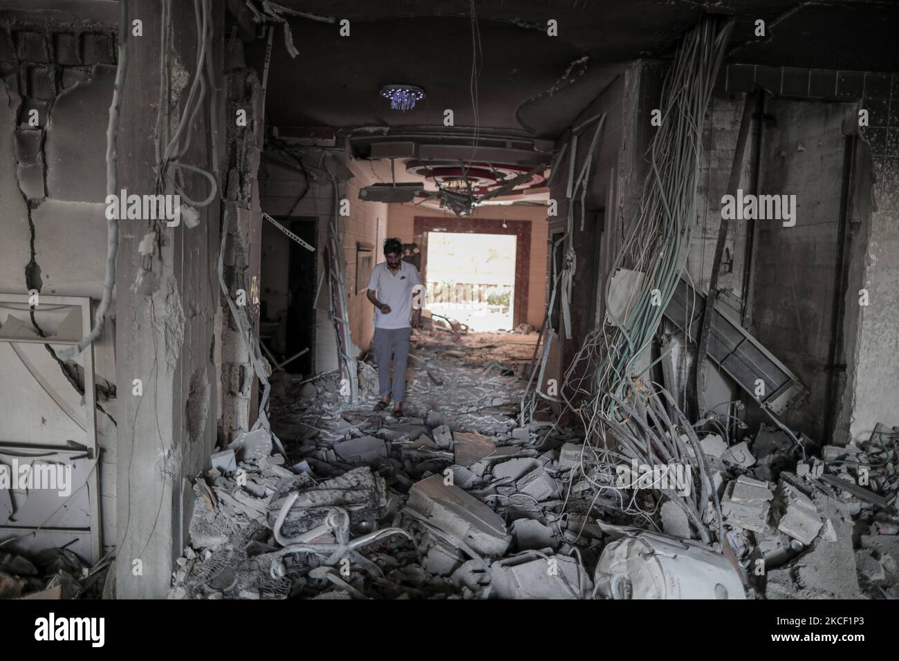 Le persone ispezionano un buco e le macerie di un edificio residenziale distrutto che è stato colpito da attacchi aerei israeliani, a Gaza City, giovedì 20 maggio 2021.(Photo by Momen Faiz/NurPhoto) Foto Stock