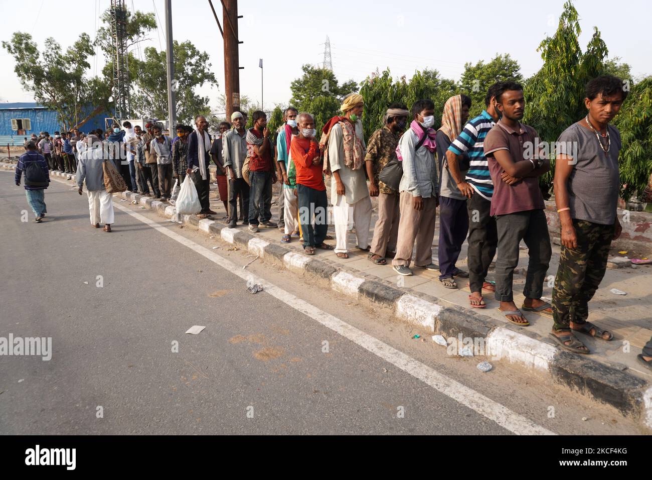 I senzatetto e i lavoratori salariali quotidiani, che lottano per trovare lavoro tra le restrizioni imposte per frenare la diffusione di Covid-19, fanno la fila per ricevere cibo distribuito da volontari lungo una strada il 23 maggio 2021 a Nuova Delhi, India. (Foto di Mayank Makhija/NurPhoto) Foto Stock