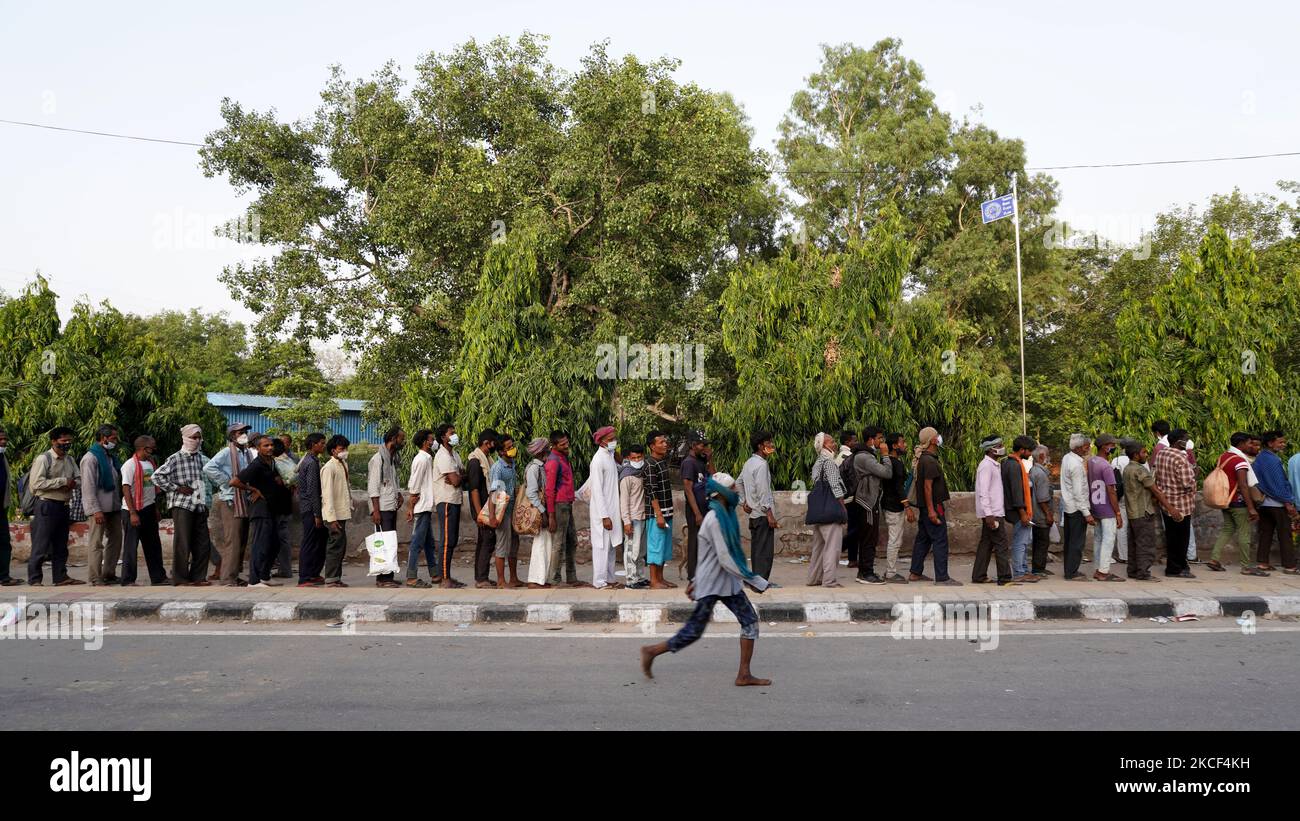 I senzatetto e i lavoratori salariali quotidiani, che lottano per trovare lavoro tra le restrizioni imposte per frenare la diffusione di Covid-19, fanno la fila per ricevere cibo distribuito da volontari lungo una strada il 23 maggio 2021 a Nuova Delhi, India. (Foto di Mayank Makhija/NurPhoto) Foto Stock