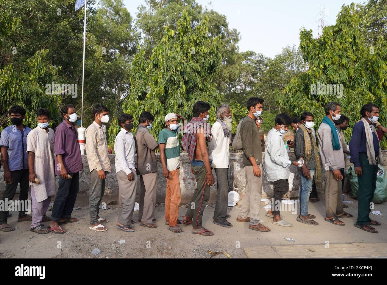 I senzatetto e i lavoratori salariali quotidiani, che lottano per trovare lavoro tra le restrizioni imposte per frenare la diffusione di Covid-19, fanno la fila per ricevere cibo distribuito da volontari lungo una strada il 23 maggio 2021 a Nuova Delhi, India. (Foto di Mayank Makhija/NurPhoto) Foto Stock
