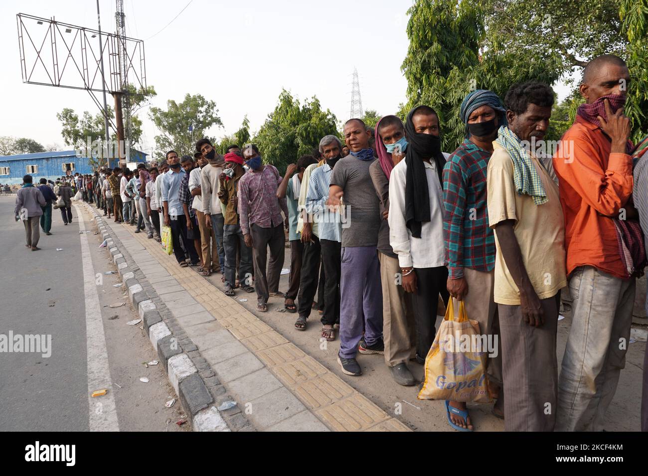 I senzatetto e i lavoratori salariali quotidiani, che lottano per trovare lavoro tra le restrizioni imposte per frenare la diffusione di Covid-19, fanno la fila per ricevere cibo distribuito da volontari lungo una strada il 23 maggio 2021 a Nuova Delhi, India. (Foto di Mayank Makhija/NurPhoto) Foto Stock