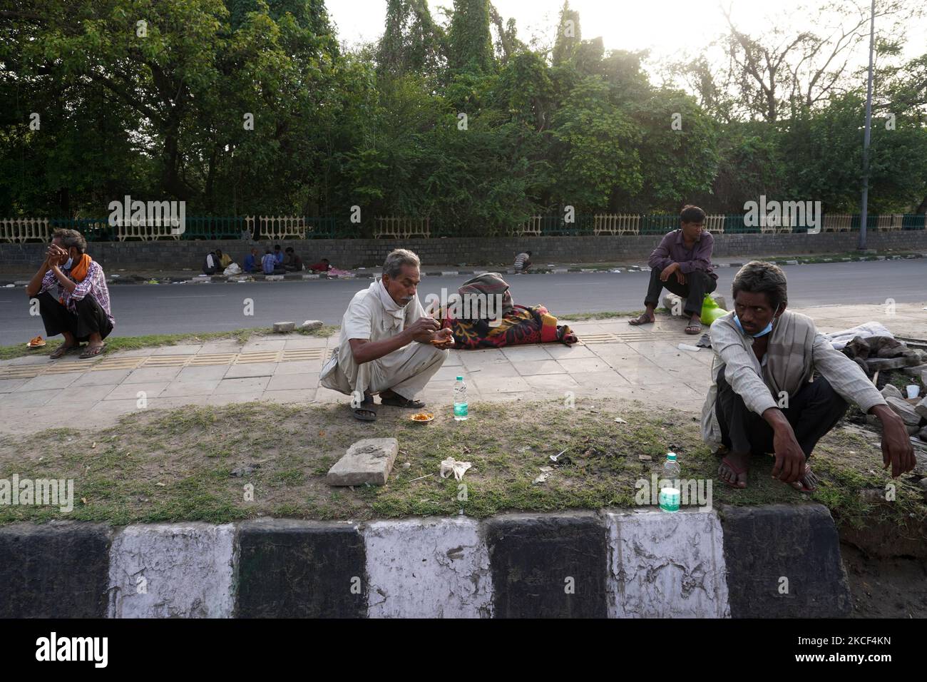 I senzatetto e i lavoratori salariali quotidiani, che lottano per trovare lavoro tra le restrizioni imposte per frenare la diffusione di Covid-19, mangiano il cibo distribuito da volontari lungo una strada il 23 maggio 2021 a Nuova Delhi, India. (Foto di Mayank Makhija/NurPhoto) Foto Stock