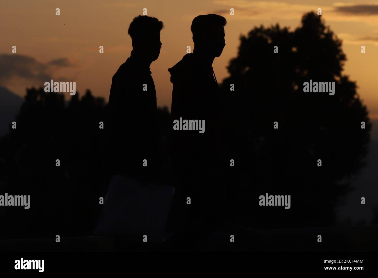 I ragazzi di Kashmiri che indossano le maschere camminano mentre il sole tramonta sul fiume Jehlum durante il COVID-19 Coronavirus a Sopore, distretto di Baramulla, Jammu e Kashmir, India il 23 maggio 2021. J&K registra 3.408 nuovi casi COVID, 48 morti; coprifuoco prorogato fino a maggio 31 (Foto di Nasir Kachroo/NurPhoto) Foto Stock