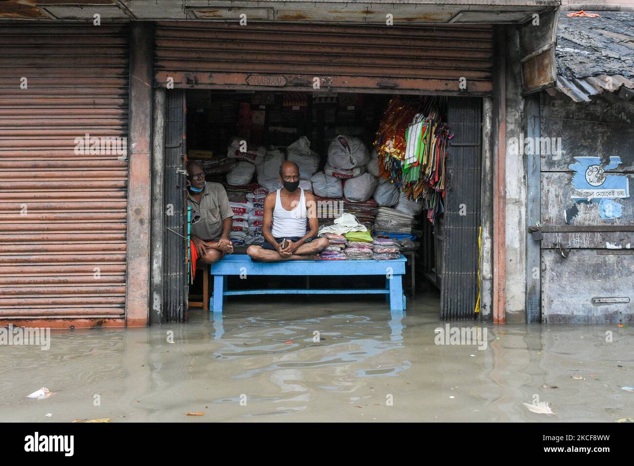 Il proprietario di un negozio attende in mezzo all'acqua profonda di inondazione del ginocchio che è causata da dopo effetto del Cyclone Yaas e dell'alta marea sul fiume Ganges a Kolkata , in India , il 26 maggio 2021 . (Foto di Debarchan Chatterjee/NurPhoto) Foto Stock