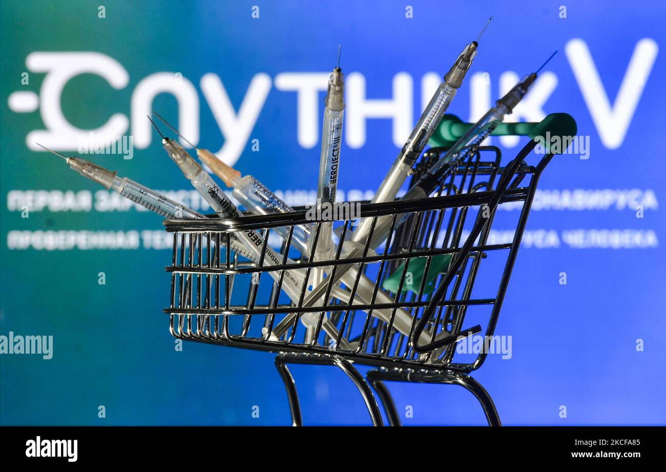 Le siringhe mediche nel mini carrello sono visibili di fronte al logo Sputnik V visualizzato su uno schermo. Venerdì 28 maggio 2021 a Dublino, Irlanda. (Foto di Artur Widak/NurPhoto) Foto Stock