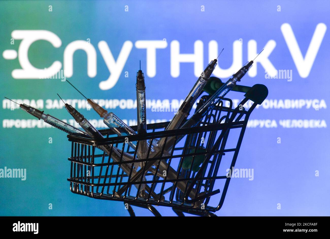 Le siringhe mediche nel mini carrello sono visibili di fronte al logo Sputnik V visualizzato su uno schermo. Venerdì 28 maggio 2021 a Dublino, Irlanda. (Foto di Artur Widak/NurPhoto) Foto Stock