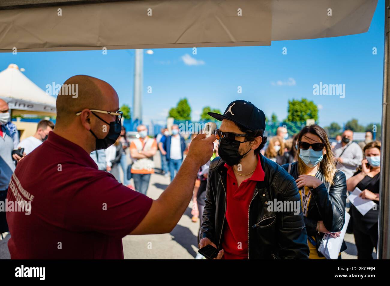 Un volontario misura la temperatura delle persone al di fuori del centro di vaccinazione prima di assumere la prima dose di vaccino il giorno aperto agli over 40s a Terlizzi, Italia, il 1 giugno 2021. A partire dal 1 giugno, i cittadini che hanno già una riserva e intendono anticipare la vaccinazione e quelli che non hanno ancora aderito alla campagna di vaccinazione hanno avuto la possibilità di accedere al banco senza la necessità di una prenotazione in alcuni centri della ASL di Bari, tra cui Terlizzi , per sottoporsi a vaccinazione. Il vaccino somministrato è il Janssen prodotto da Johnson & Johnson, dose singola. Dato l'ava Foto Stock