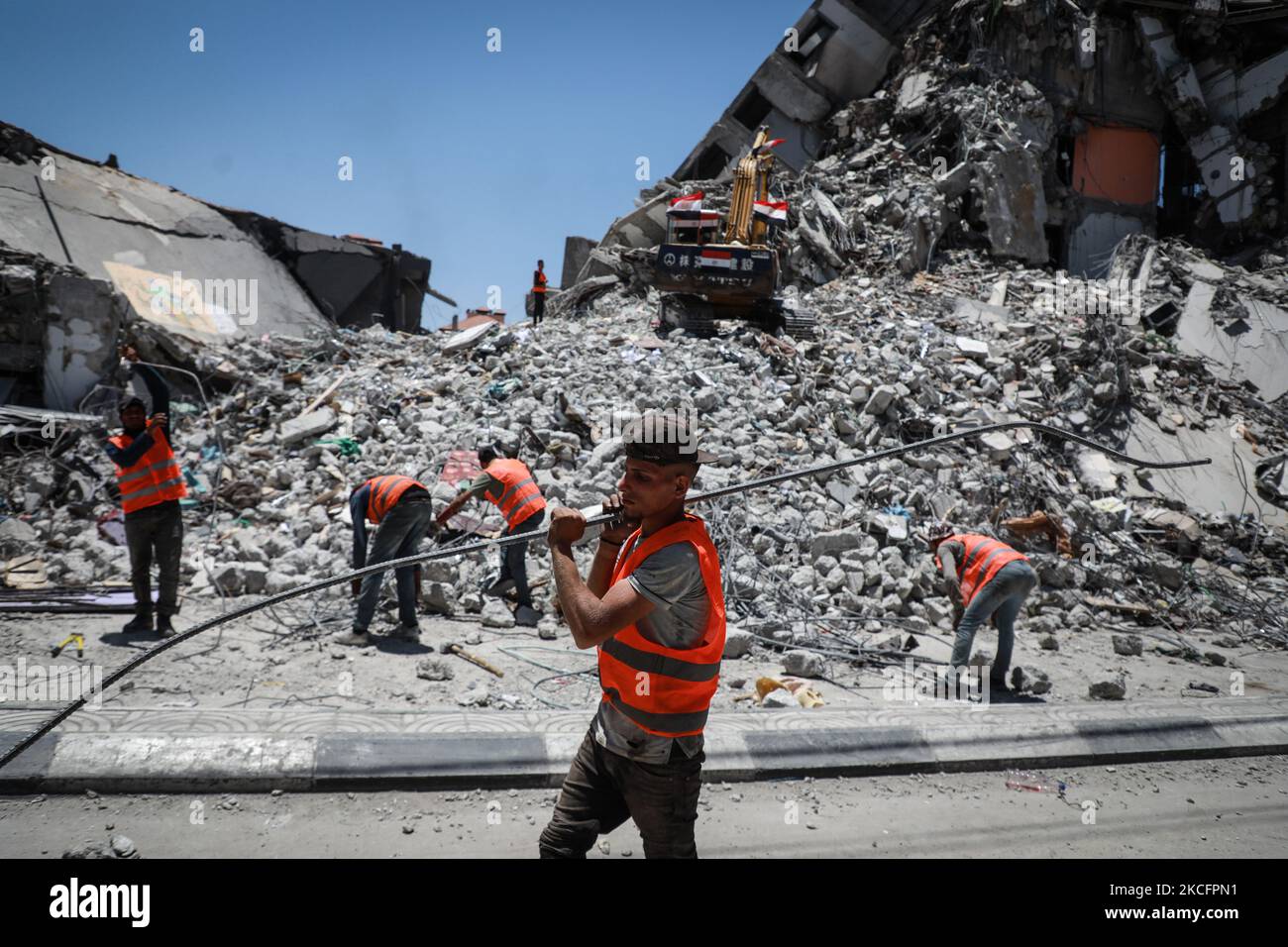 I lavoratori si accingono a sbarre di acciaio piegate come parte del riciclaggio di materiali da costruzione recuperati da edifici distrutti durante il conflitto tra Hamas e Israele del maggio 2021, lungo una strada a Gaza City il 7 giugno 2021. (Foto di Majdi Fathi/NurPhoto) Foto Stock