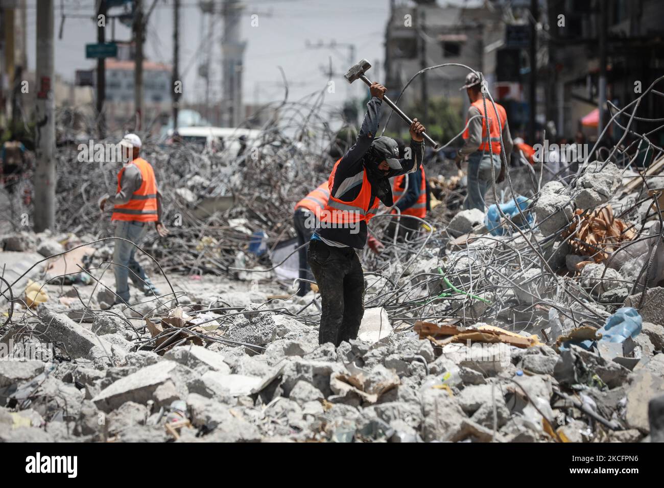 I lavoratori si accingono a sbarre di acciaio piegate come parte del riciclaggio di materiali da costruzione recuperati da edifici distrutti durante il conflitto tra Hamas e Israele del maggio 2021, lungo una strada a Gaza City il 7 giugno 2021. (Foto di Majdi Fathi/NurPhoto) Foto Stock