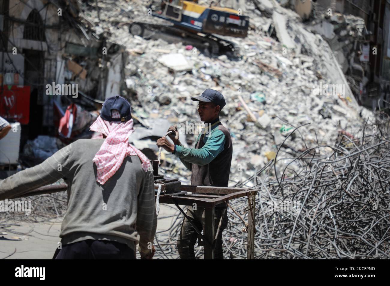 I lavoratori si accingono a sbarre di acciaio piegate come parte del riciclaggio di materiali da costruzione recuperati da edifici distrutti durante il conflitto tra Hamas e Israele del maggio 2021, lungo una strada a Gaza City il 7 giugno 2021. (Foto di Majdi Fathi/NurPhoto) Foto Stock