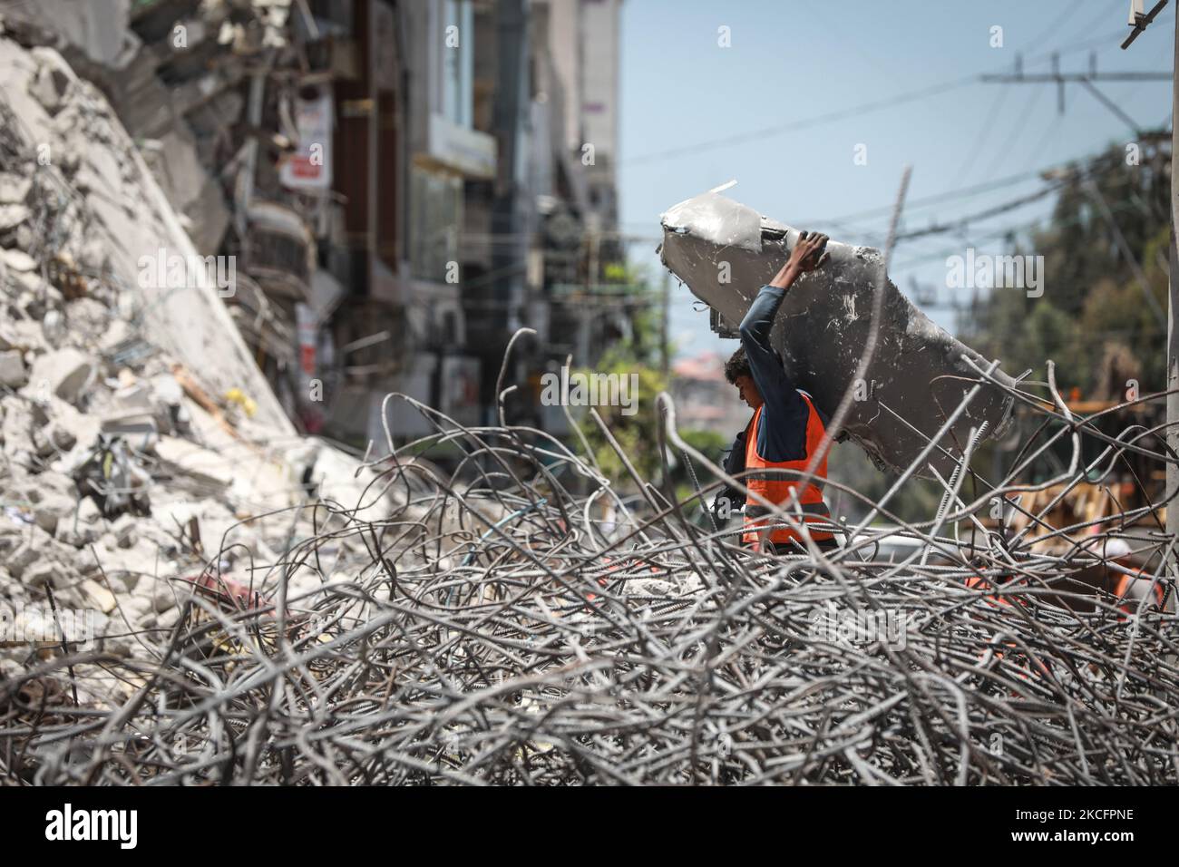 I lavoratori si accingono a sbarre di acciaio piegate come parte del riciclaggio di materiali da costruzione recuperati da edifici distrutti durante il conflitto tra Hamas e Israele del maggio 2021, lungo una strada a Gaza City il 7 giugno 2021. (Foto di Majdi Fathi/NurPhoto) Foto Stock