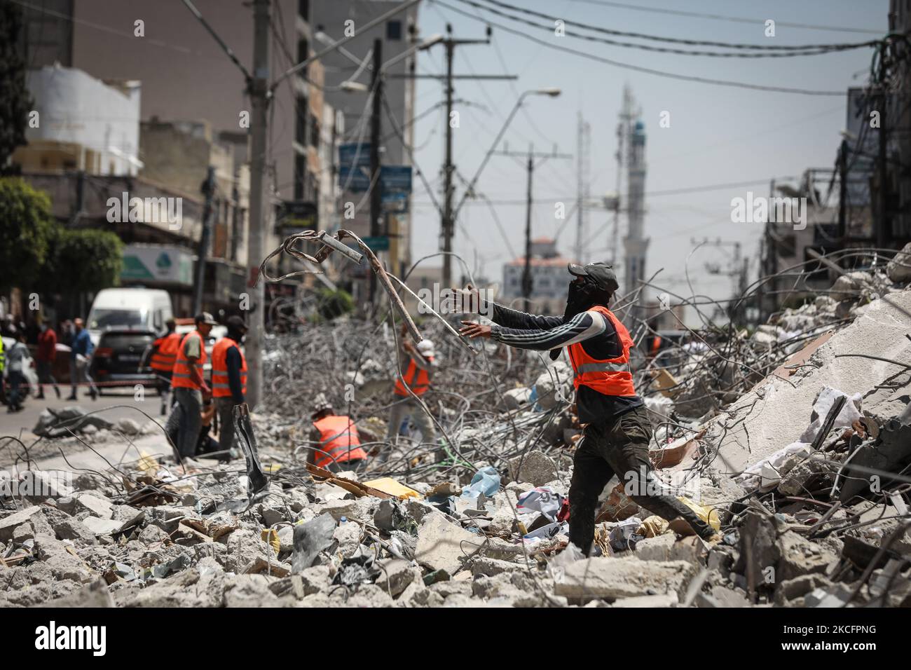 I lavoratori si accingono a sbarre di acciaio piegate come parte del riciclaggio di materiali da costruzione recuperati da edifici distrutti durante il conflitto tra Hamas e Israele del maggio 2021, lungo una strada a Gaza City il 7 giugno 2021. (Foto di Majdi Fathi/NurPhoto) Foto Stock