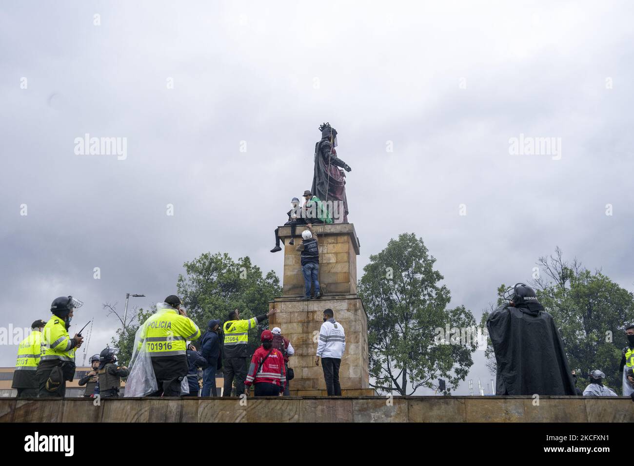 Gli indigeni di Misak si trovano di fronte ai poliziotti mentre protestano accanto alla statua della regina Isabel di Spagna il 09 giugno 2021 a Bogotà, Colombia. Un altro giorno di proteste a Bogotà Colombia, oggi in compagnia degli indigeni Misak che fingettero di abbattere la statua di ''Isabel il cattolico'' e Cristobal Colon conquistatore d'America. (Foto di David Rodriguez/NurPhoto) Foto Stock