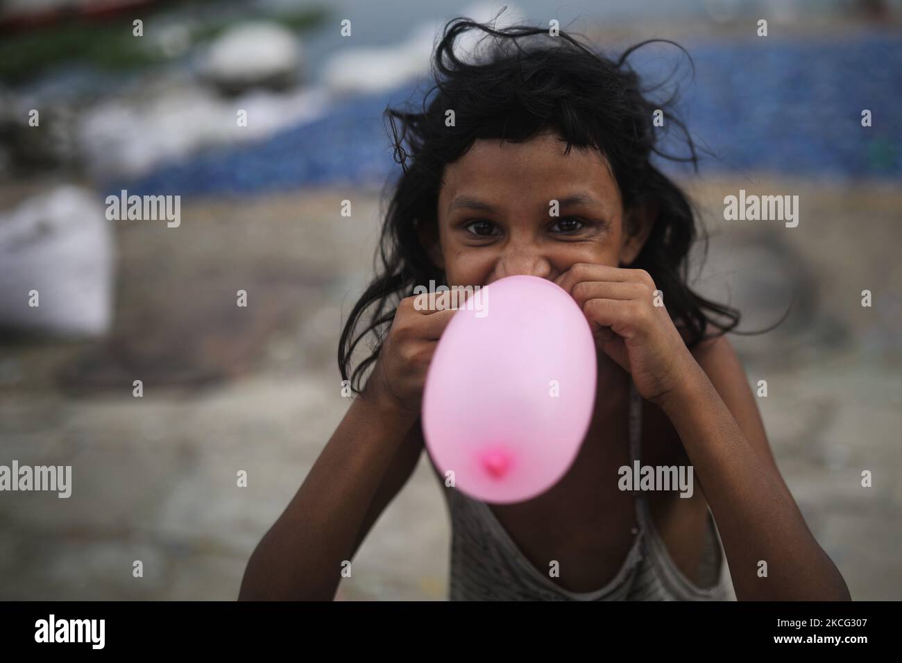 Un bambino reagisce alla macchina fotografica mentre pompa un pallone in un'area a basso reddito a Dhaka, Bangladesh il 14 giugno 2021. (Foto di Syed Mahamudur Rahman/NurPhoto) Foto Stock