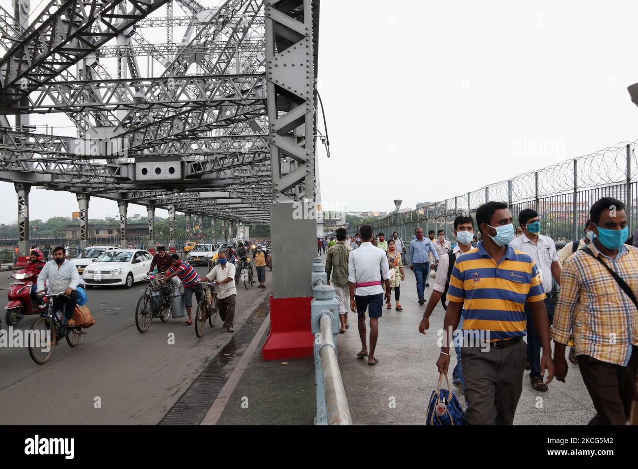 I pendolari con equipaggiamento protettivo passeranno davanti al caratteristico Ponte Howrah sul Fiume Ganga e andranno al luogo di lavoro a Kolkata il 16,2021 Giugno. Dopo che il governo dello stato del Bengala Occidentale ha allentato le restrizioni di blocco per frenare la diffusione del coronavirus Covid-19. Gli uffici governativi e privati sono stati autorizzati a funzionare con il 25% di personale a partire dal 16 giugno (mercoledì). Annunciando nuovi protocolli dal giugno 16, il Mamata Banerjee, ministro principale del Bengala occidentale ha guidato l'amministrazione ha esteso i cordoli in corso per combattere la pandemia per altri 15 giorni fino al giugno 30. (Foto di Debajyoti Chakraborty/NurPhoto) Foto Stock