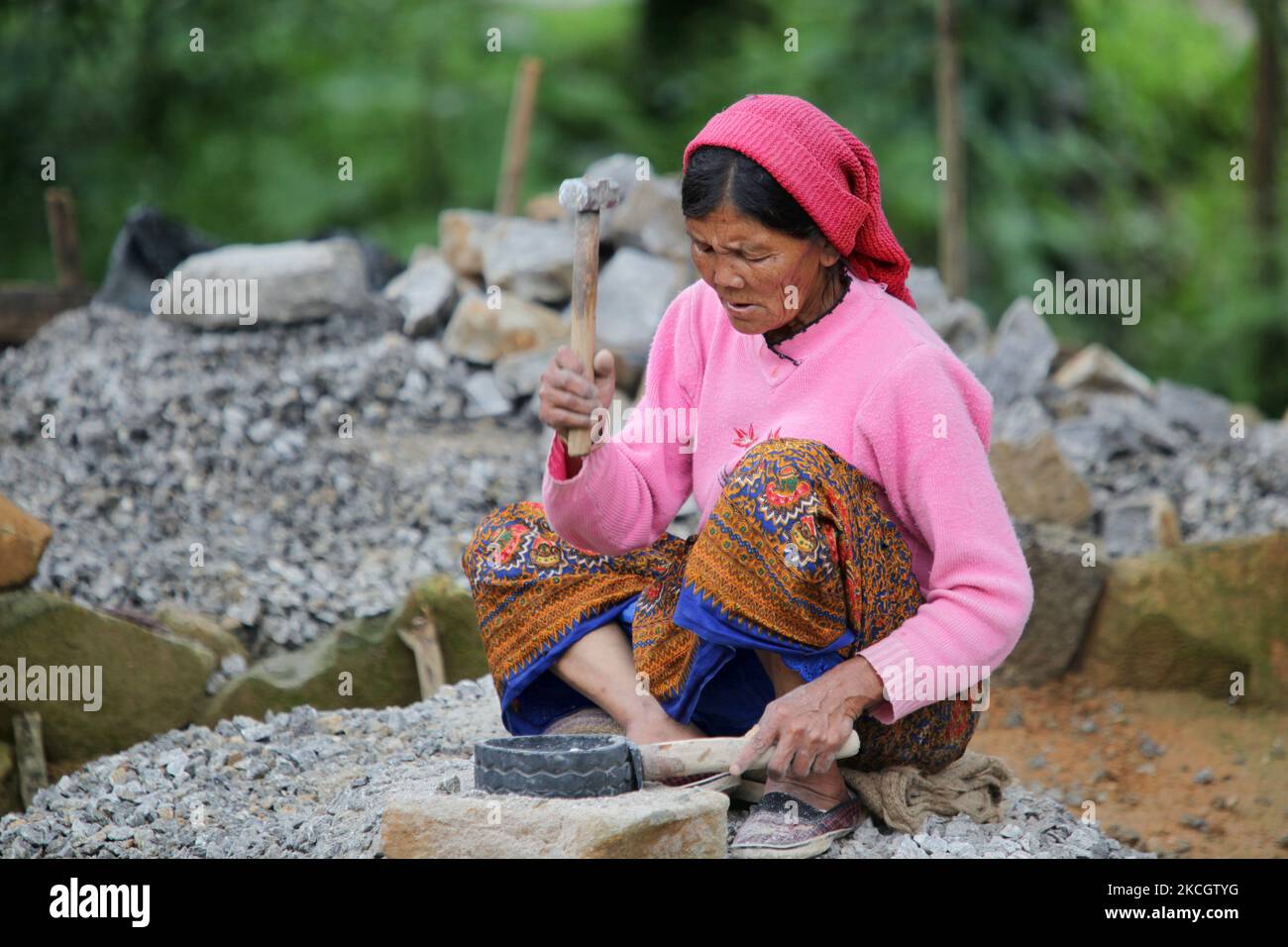 La donna nepalese lavora sassi in ghiaia con un attrezzo di gomma con un manico di legno ed un piccolo martello in Khechuperi, Sikkim, India. La ghiaia sarà usata per fare cemento per costruzione. (Foto di Creative Touch Imaging Ltd./NurPhoto) Foto Stock