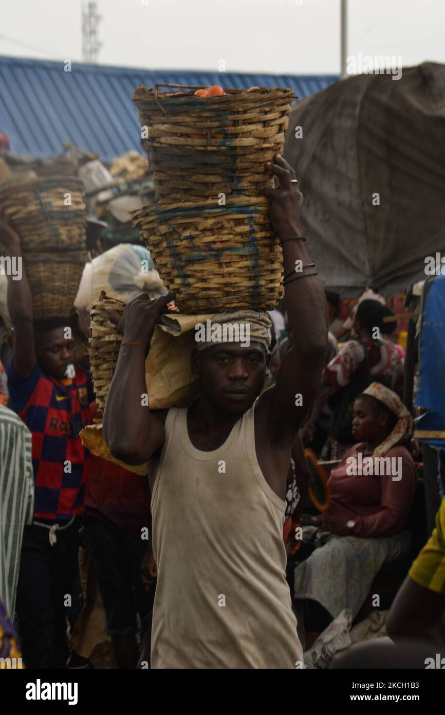 Un lavoratore porta un paniere di pomodori al mercato Mile 12 a Lagos, i prezzi dei prodotti alimentari rimangono elevati nonostante il calo del tasso di inflazione al 17,93% nel maggio 2021, il 7 luglio 2021. La Banca Mondiale ha affermato che l’aumento dell’inflazione e dei prezzi del paese hanno spinto circa sette milioni di nigeriani al di sotto della soglia di povertà nel 2020. L'aumento dell'indice alimentare è stato causato dall'aumento dei prezzi del pane, dei cereali, del latte, del formaggio, delle uova, Pesce, bevande analcoliche, caffè, tè e cacao, frutta, Carne, oli e grassi, e vegetali. (Foto di Olukayode Jaiyeola/NurPhoto) Foto Stock