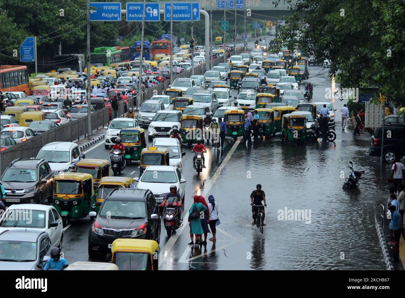 I pendolari aspettano i trasporti pubblici lungo una strada allagata dopo le forti piogge a Nuova Delhi, India, il 14 luglio 2021. La pioggia monsonica ha fornito un certo sollievo ai residenti dall'estate ardente ma anche causato il disboscamento dell'acqua e gli ingorghi del traffico in parecchie parti della capitale nazionale. (Foto di Mayank Makhija/NurPhoto) Foto Stock