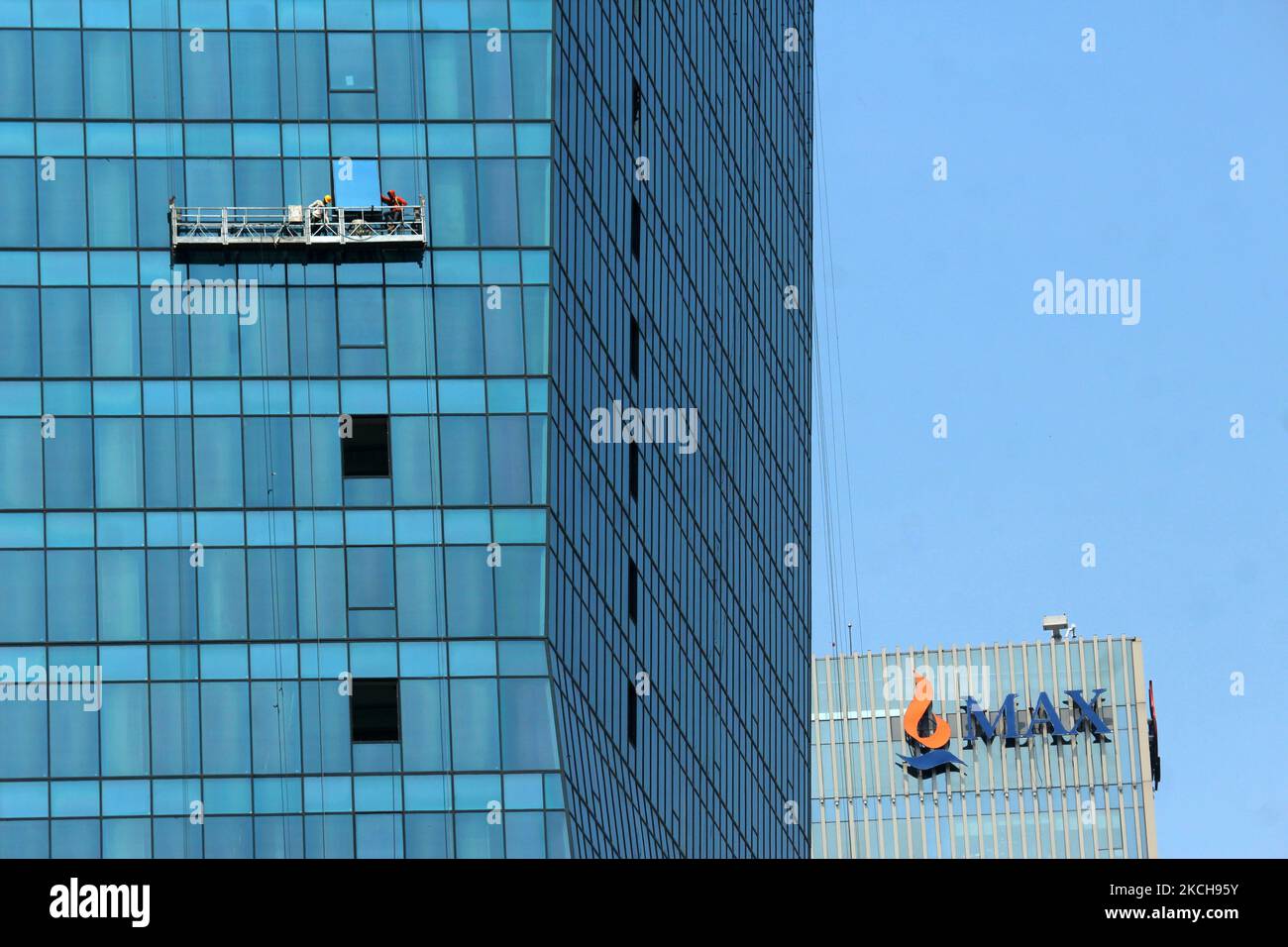 Un lavoratore pulisce il vetro esterno di un edificio nel centro commerciale di Noida, un sobborgo di Nuova Delhi, India il 15 luglio 2021. (Foto di Mayank Makhija/NurPhoto) Foto Stock