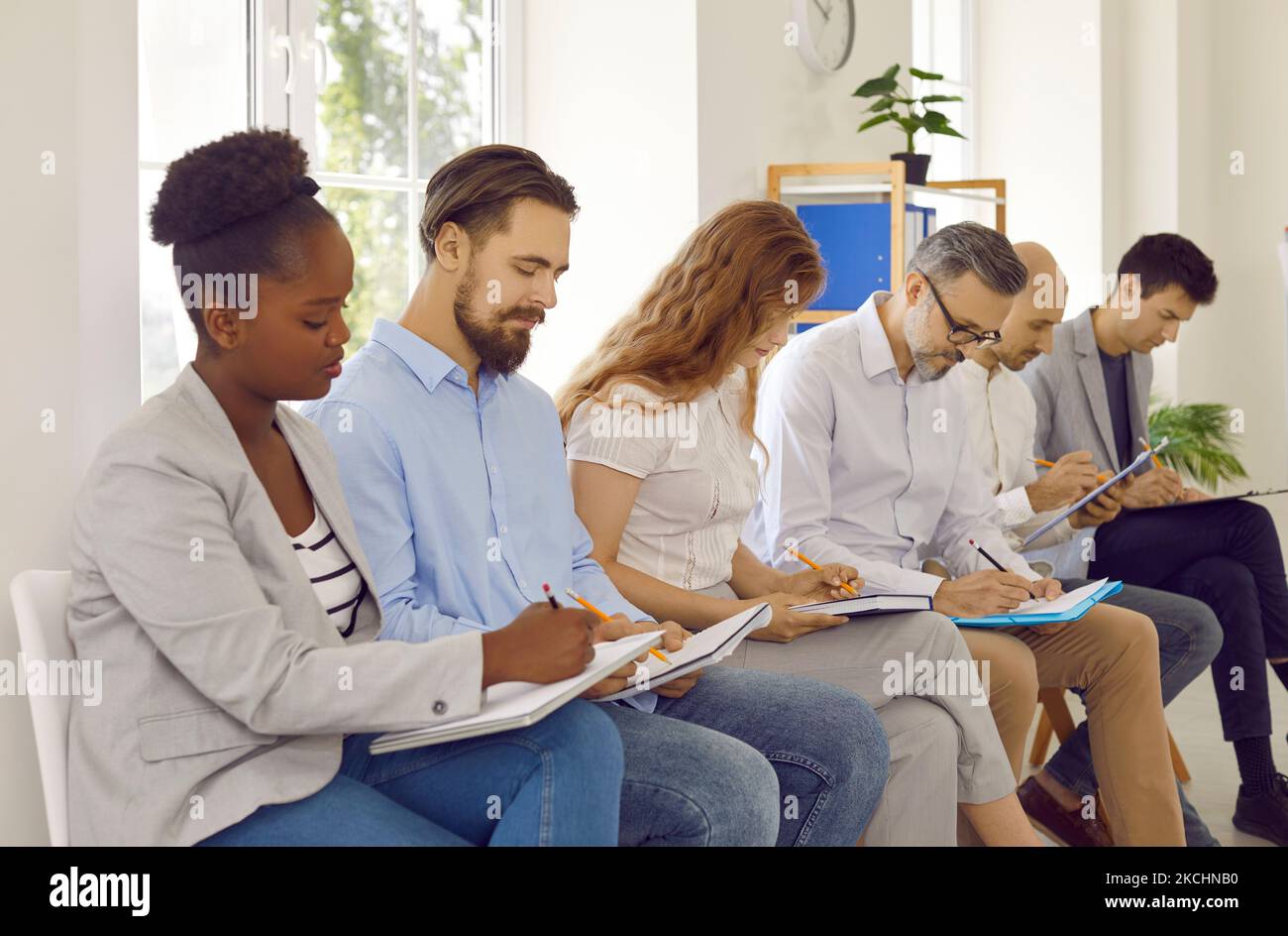 Gruppo internazionale uomini d'affari che studiano scrittura facendo note ascoltare la presentazione in ufficio. Foto Stock