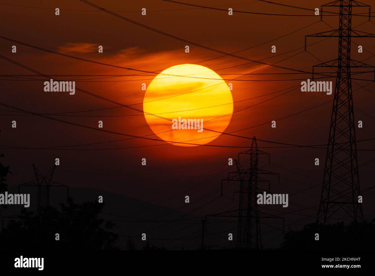 Tramonto estivo in Grecia con piloni elettrici vicino alla città di Salonicco. Pali dell'elettricità ad alta tensione - torri durante il tramonto nell'ora magica. Le torri metalliche, come si vede al tramonto nella campagna greca, distribuiscono energia elettrica dalla centrale elettrica dove viene generata elettricità nella produzione di carbone, in tutto il paese. I fili elettrici, la griglia e le colonne o i piloni elettrici sono visti come silhouette nel cielo notturno colorato e crepuscolo. Oreokastro, Salonicco in Grecia il 25 luglio 2021 (Foto di Nicolas Economou/NurPhoto) Foto Stock