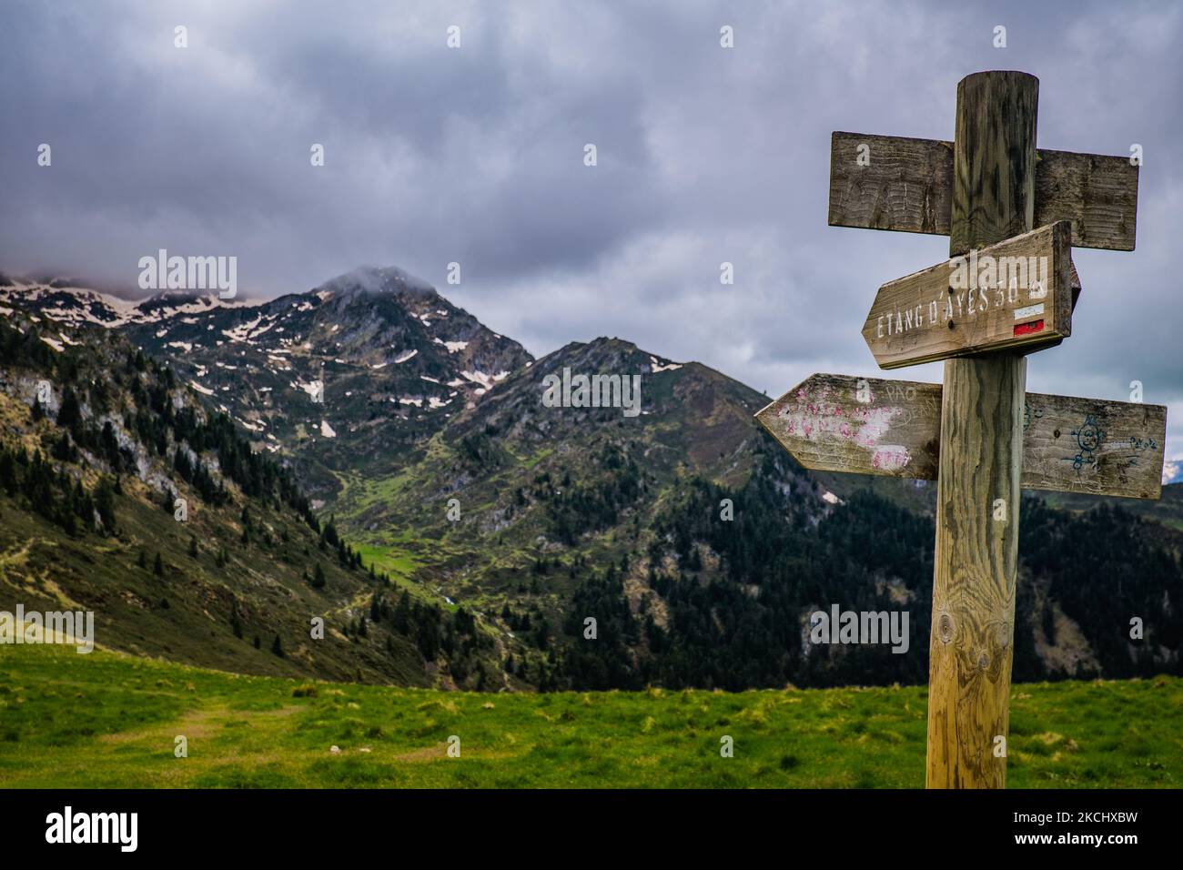 Indicazioni stradali con montagne innevate sullo sfondo vicino al lago Ayes la catena montuosa dei Pirenei francesi Foto Stock