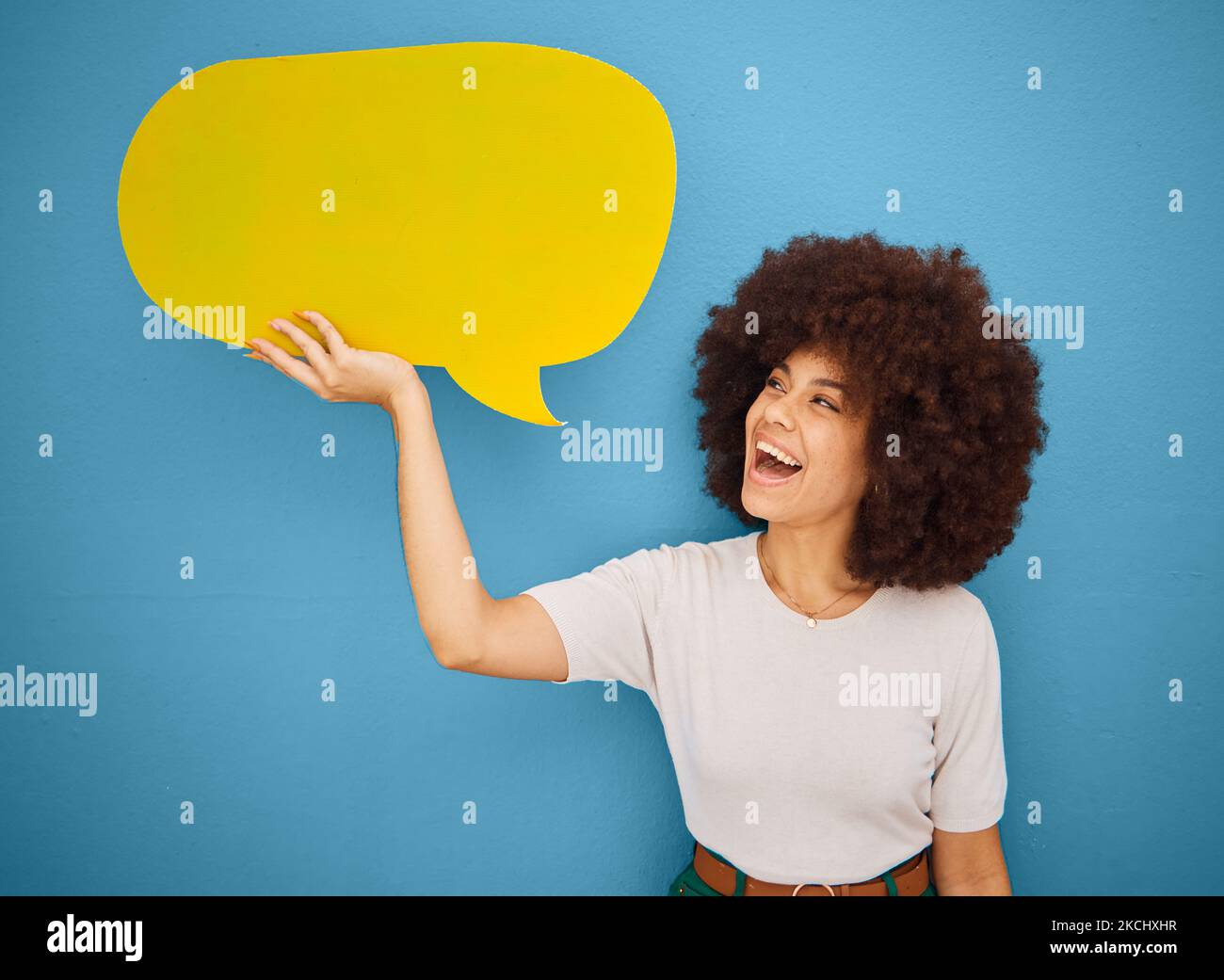 Donna nera con bolla di linguaggio giallo, afro e sfondo blu mockup spazio per la pubblicità o il posizionamento del prodotto. Sorriso, annuncio segno e donna Foto Stock