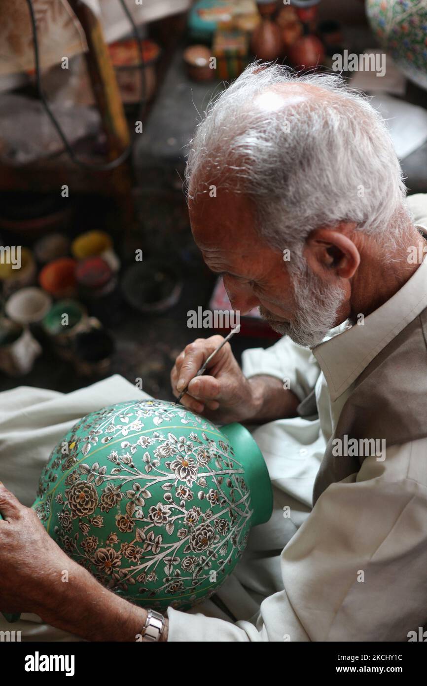 Un artigiano Kashmiri di 78 anni dipinge un disegno intricato su un vaso di carta in un laboratorio galleggiante lungo dal Lake a Srinagar, Kashmir, India, il 26 giugno 2010. (Foto di Creative Touch Imaging Ltd./NurPhoto) Foto Stock