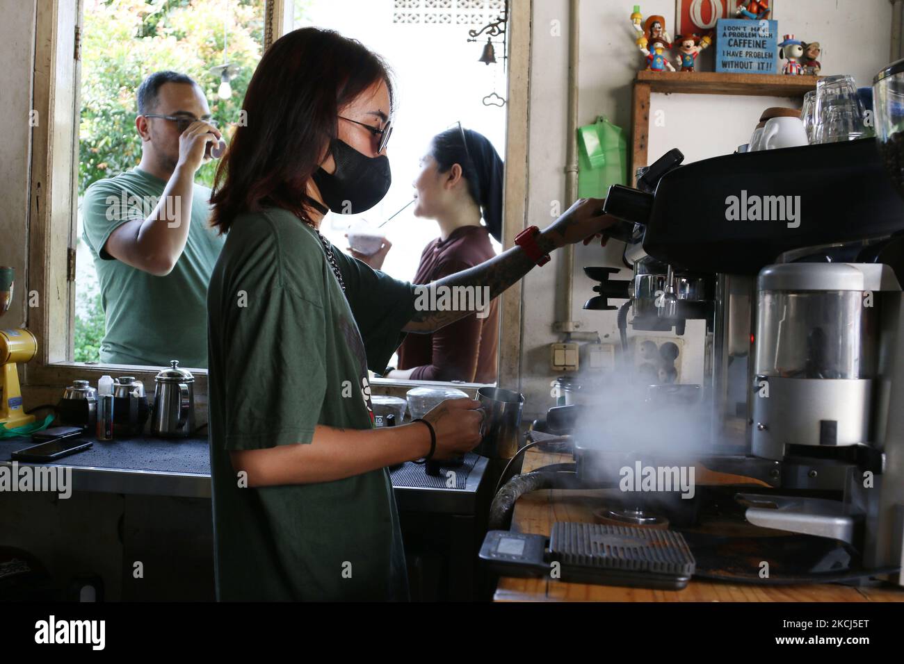 I clienti si crogiolano nel cortile della caffetteria Nyambi a Depok, Giava Occidentale, Indonesia, il 3,2021 agosto. La caffetteria Nyambi Ngopi di Depok ha fatto la sua pagina per il programma caffè mentre prendisole alle 09,00 - 10,00 WIB. Il proprietario del negozio spera che questo programma possa promuovere una cultura di godere del caffè con uno stile di vita sano, e la sua attività di bar può sopravvivere e rimbalzare di nuovo da condizioni difficili applicando protocolli di salute. (Foto di Dasril Roszandi/NurPhoto) Foto Stock