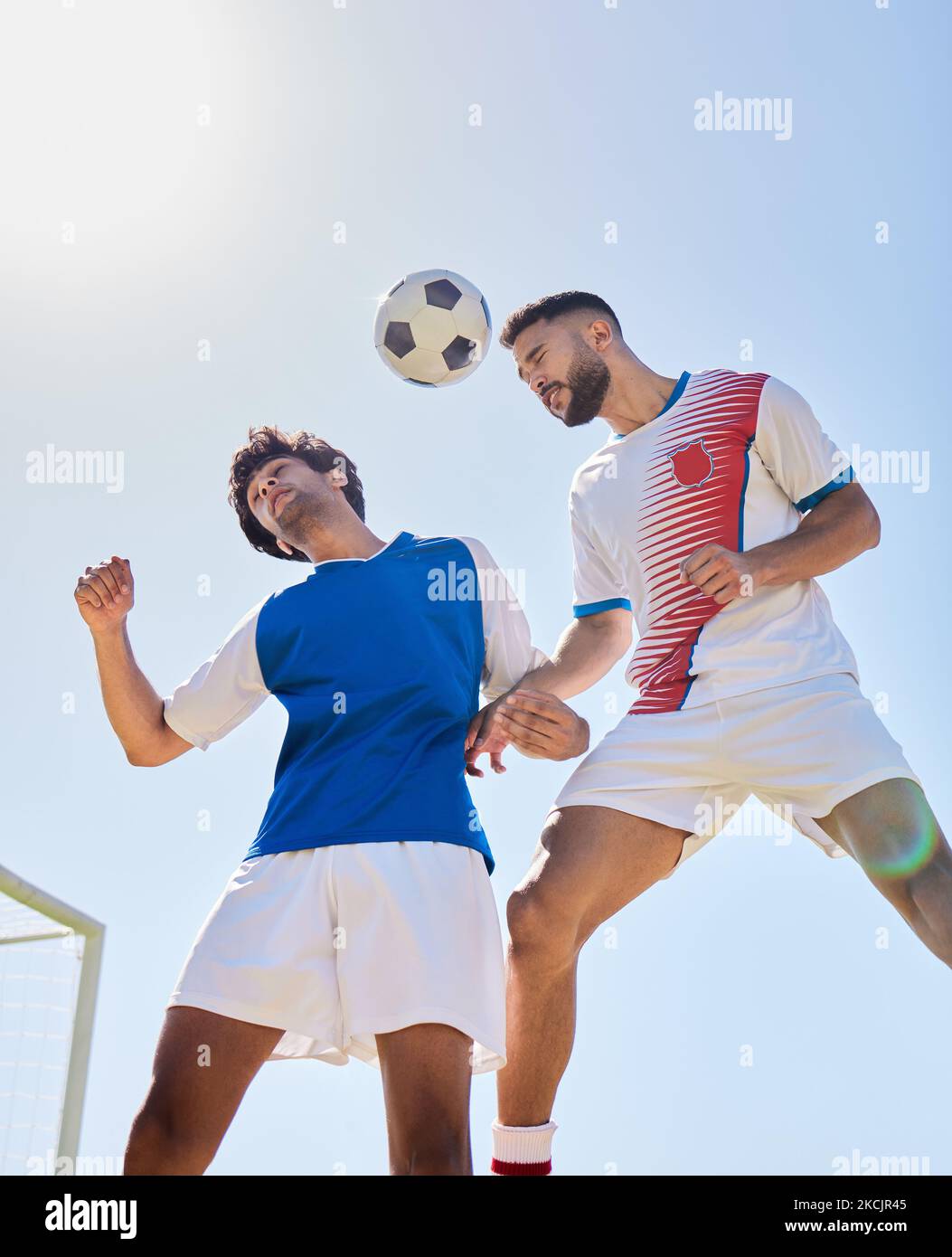 Calcio, sport e fitness, uomini con pallone da calcio partita, rivale e salto sul campo sportivo all'aperto. Giocatore di calcio, esercizio fisico e gioco di atleta Foto Stock
