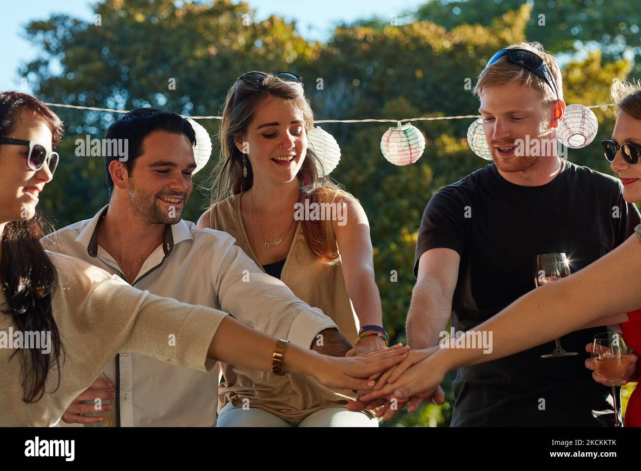 La banda del fine settimana si raduna: Un gruppo di giovani amici felici che mettono le mani in un mucchio durante una festa all'aperto. Foto Stock