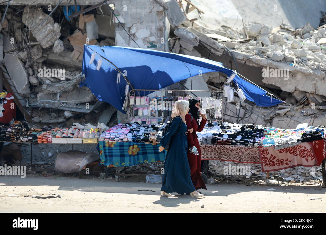 Le donne fanno shopping vicino alle macerie degli edifici distrutti colpiti dagli attacchi aerei israeliani durante una guerra di 11 giorni tra i governanti di Hamas di Gaza e Israele, sulla principale strada dello shopping a Gaza City, il 28 settembre 2021. (Foto di Majdi Fathi/NurPhoto) Foto Stock