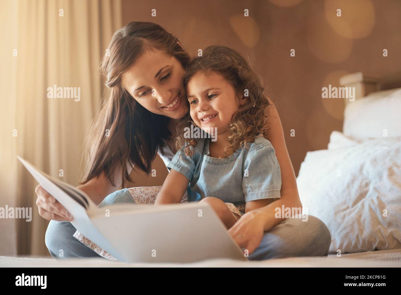I bambini hanno pensieri infiniti di immaginazione, una madre e una figlia felici a casa che leggono un libro di storia sul letto. Foto Stock
