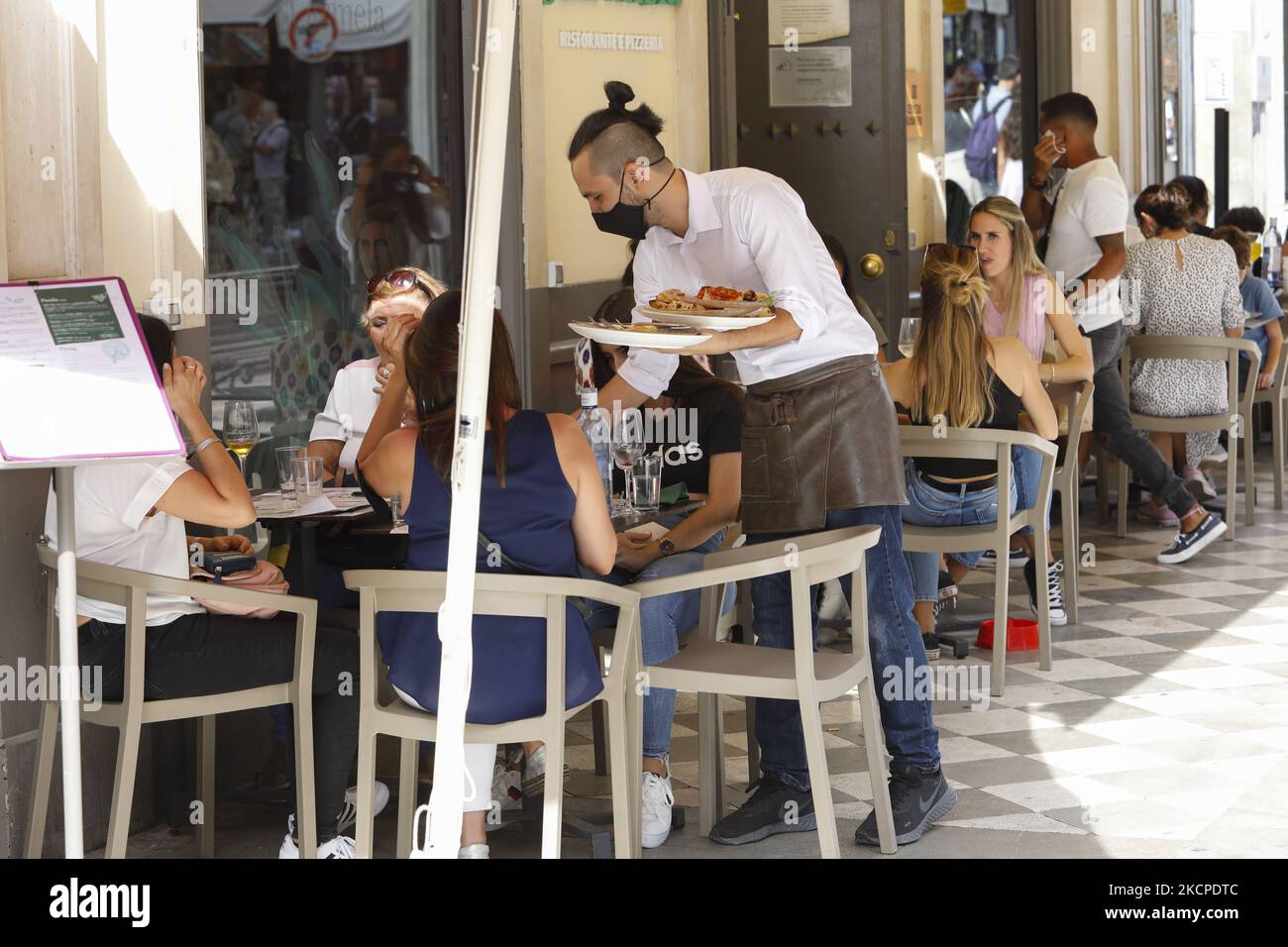 Un cameriere con una maschera contro il coronavirus serve alcuni piatti in una terrazza bar durante il Pilar e il fine settimana lungo Giornata Nazionale a Granada, Spagna il 11 ottobre 2021. La gente del posto apprezza il bel tempo mangiando o camminando per le strade di Granada, come molti turisti vengono a visitare la città durante questi festeggiamenti. (Foto di Ãlex CÃ¡mara/NurPhoto) Foto Stock