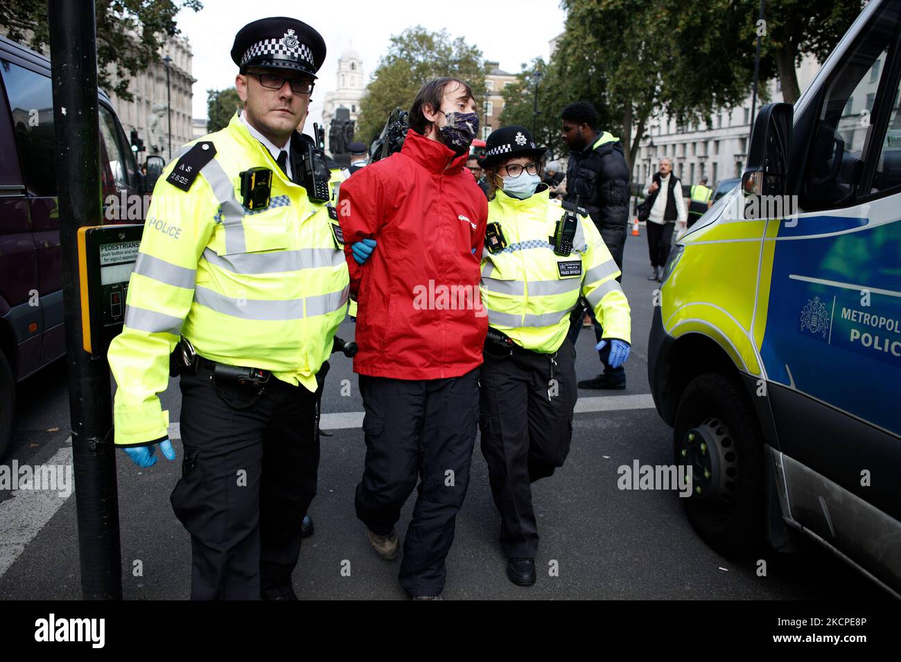 I poliziotti arrestano un attivista di Greenpeace liberato dal fatto di essere 'bloccato' su un tamburo petrolifero fuori dalle porte di Downing Street a Whitehall a Londra, in Inghilterra, il 11 ottobre 2021. La protesta, alla quale gli attivisti portarono anche una statua di pietra macchiata di petrolio del primo ministro britannico Boris Johnson, fu messa in scena per protestare il permesso richiesto dalla società energetica Siccar Point dalle autorità britanniche per la perforazione nel giacimento petrolifero di Cambo nel Mare del Nord. (Foto di David Cliff/NurPhoto) Foto Stock